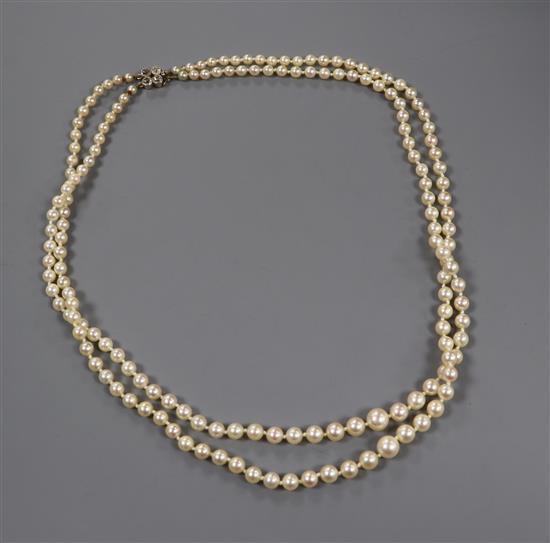 A twin strand graduated cultured pearl necklace with yellow metal and four stone diamond set clasp, 52cm
